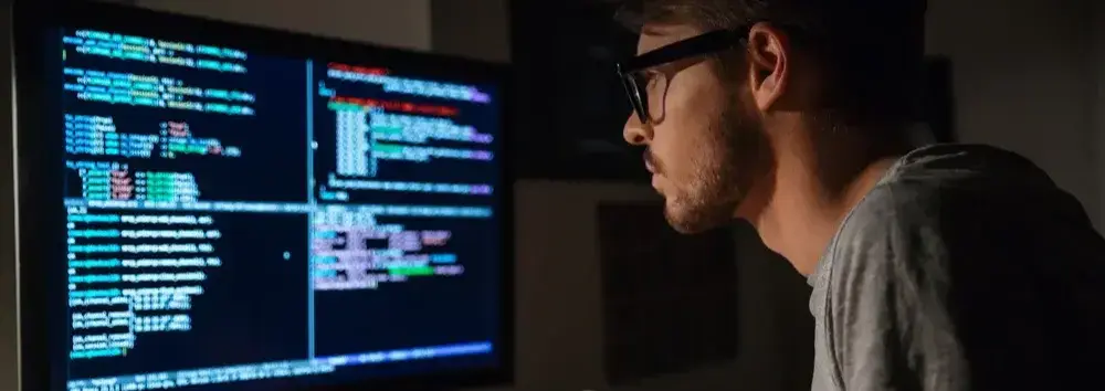 Profile of concentrated young software developer eating pizza and coding at home-1